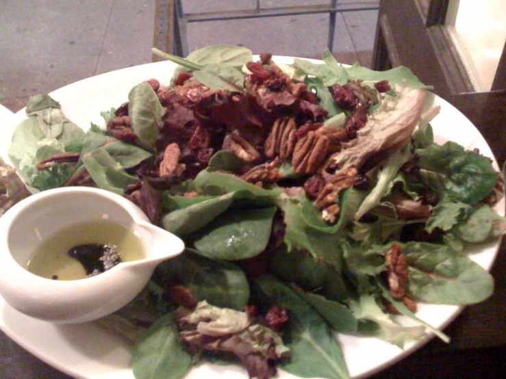 a white plate with green leaves and a salad