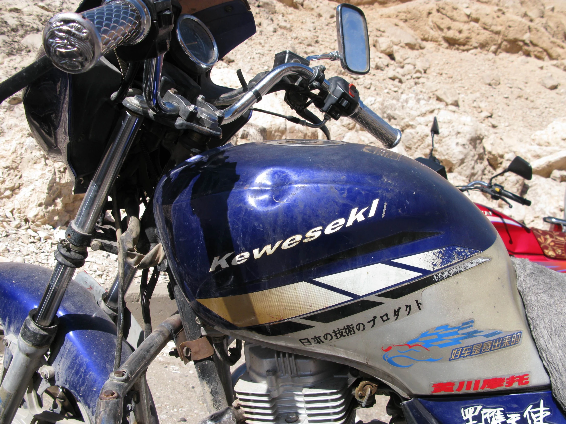 the side view of a blue motorcycle parked on the rocks