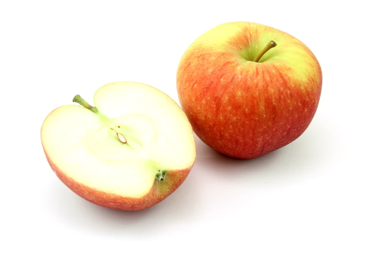 two apples sit side by side with one being sliced in half