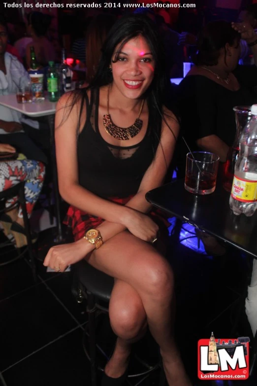 a pretty young lady sitting in a bar with her leg up