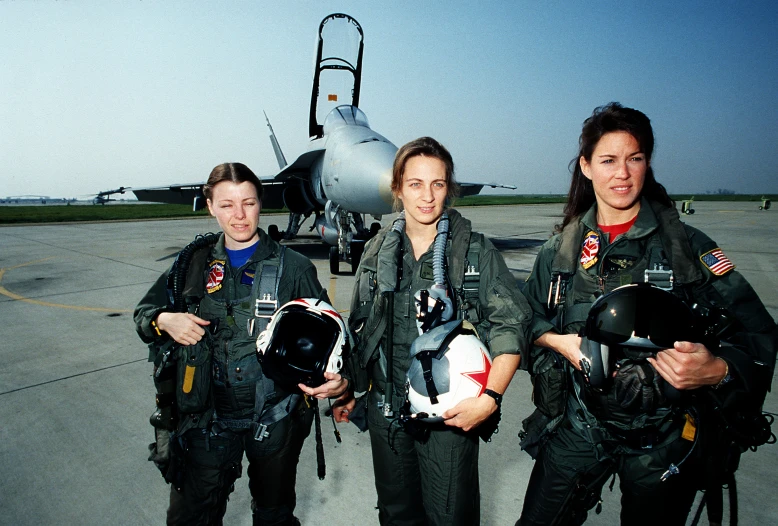 a group of women standing next to each other near a plane