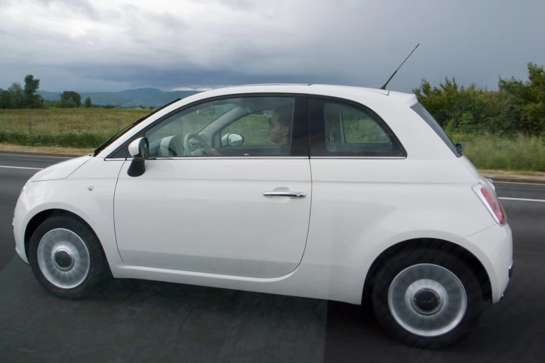 a smart car with chrome rims drives down the road