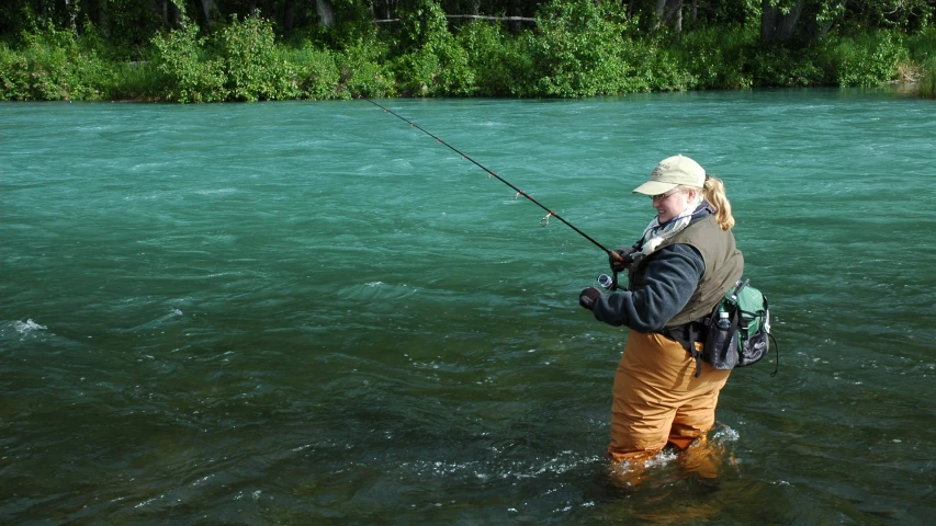 a man standing in the water holding onto a fishing pole