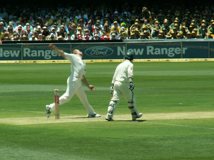 two people playing a game of cricket on a grass covered field