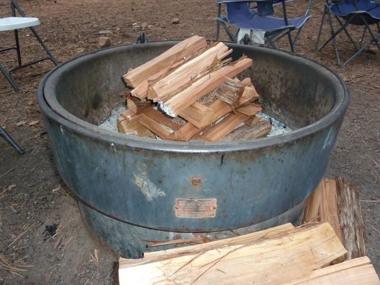 a large metal pot filled with logs near chairs