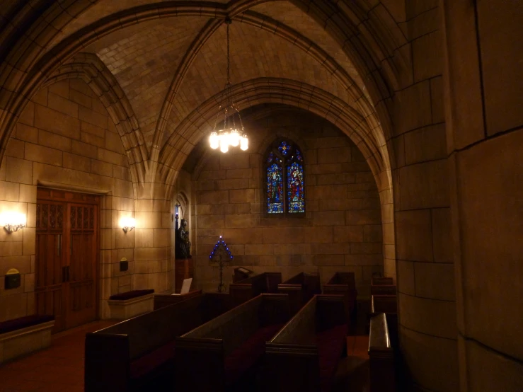 empty pews in a dark cathedral with high stained glass windows