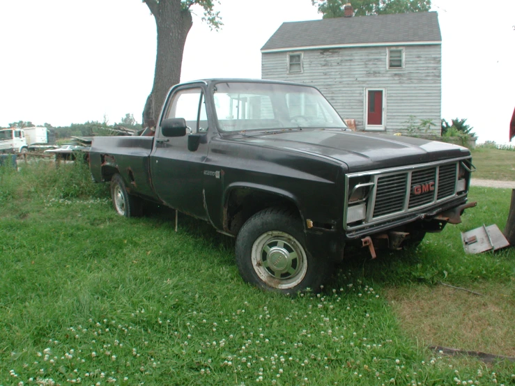 old truck sitting in the grass near a tree