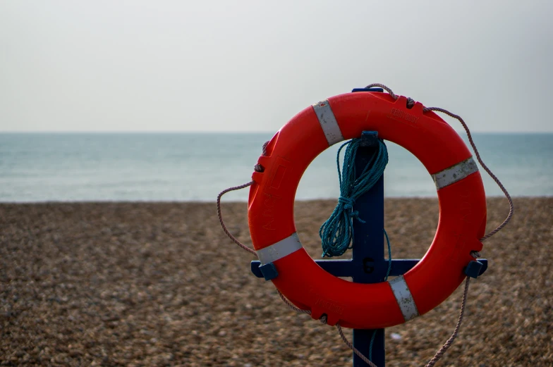 an life preserver sits on the beach against a background of blue and grey skies