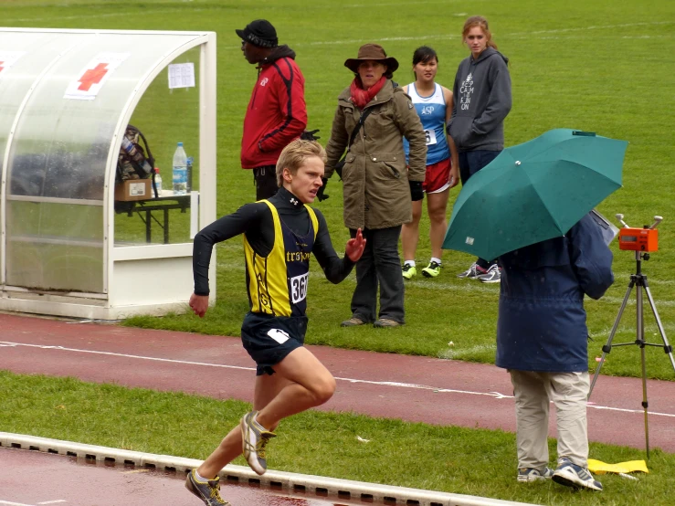 a person runs along a track under an umbrella