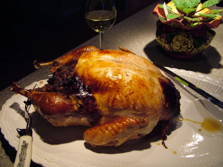 a thanksgiving turkey sits on a plate next to a glass of wine