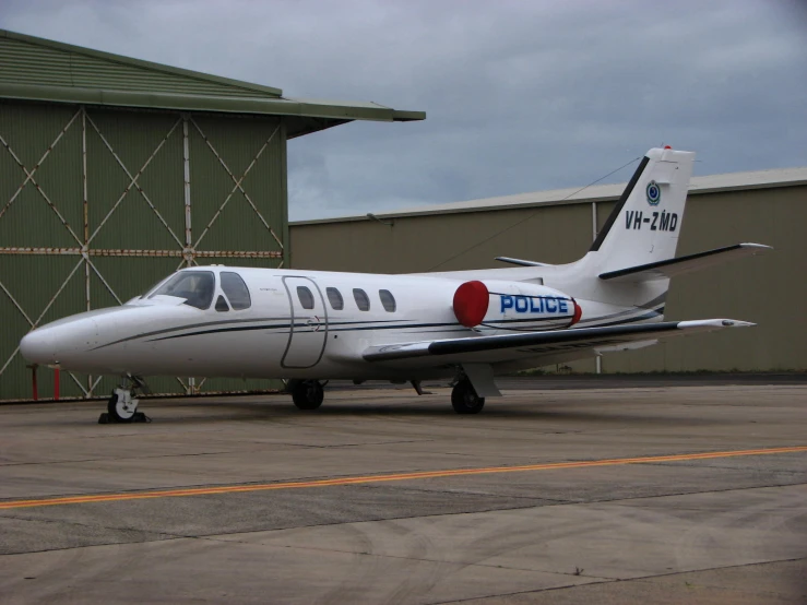 a small police jet parked next to a green building