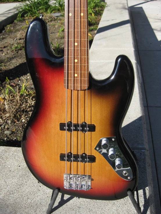 an electric bass guitar sitting on concrete outside