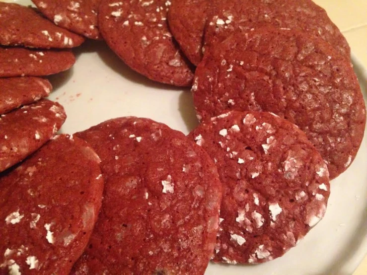 a white plate topped with red cookies and powdered sugar