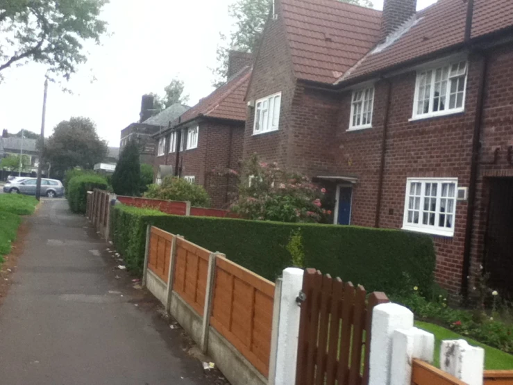 several houses with bushes and cars parked on the side