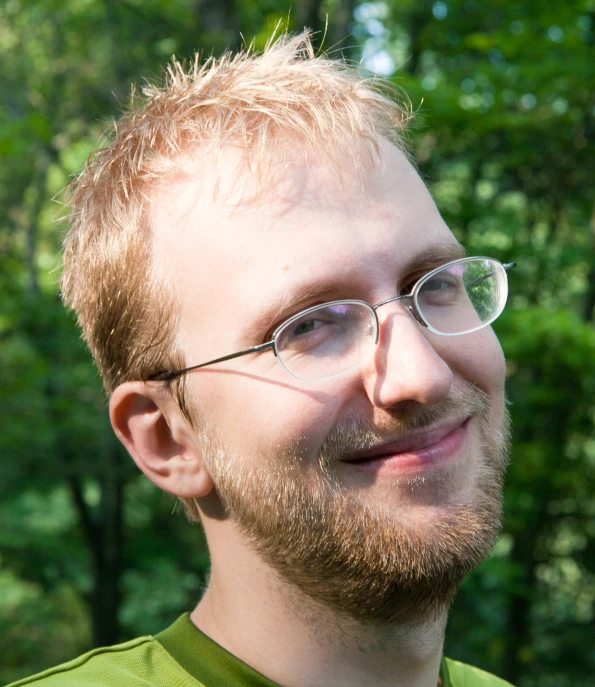 a man in glasses smiles at the camera