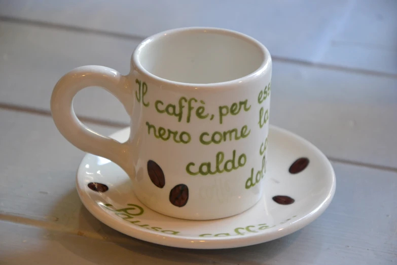 a coffee cup and saucer with italian words painted on it