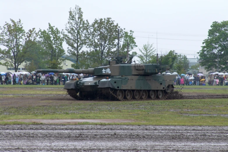 tanks on a field in front of a large crowd