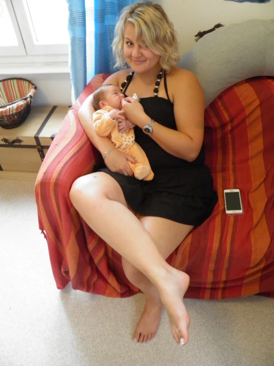 a woman is holding a baby and sitting in a chair