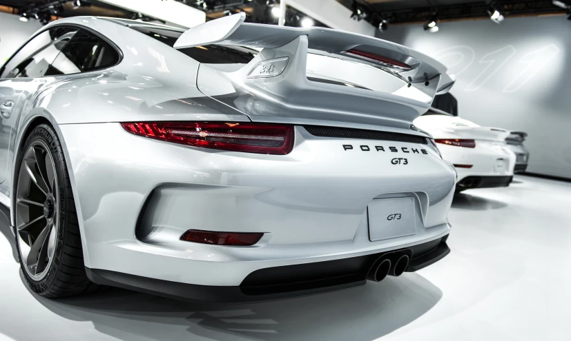 two porsches sit in the showroom and look like they could be driven on the tracks
