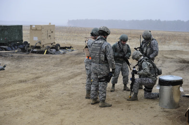 four soldiers are standing in the dirt with a gun and knife