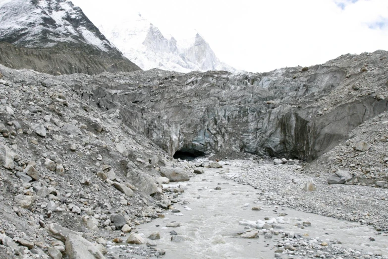 a mountain with rocks in the river, and a large hole in the side