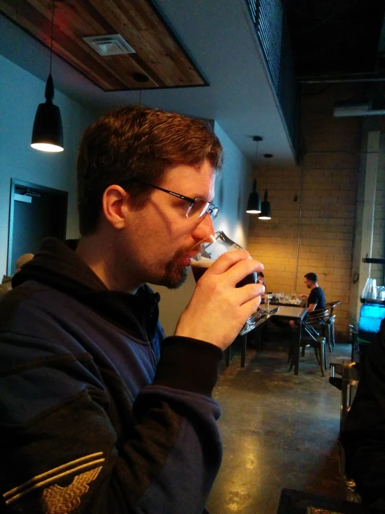 a man drinking some beer from a wine glass