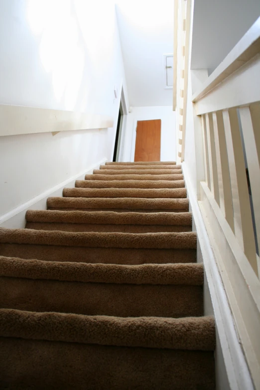 a brown and white staircase with a light that is shining on the door