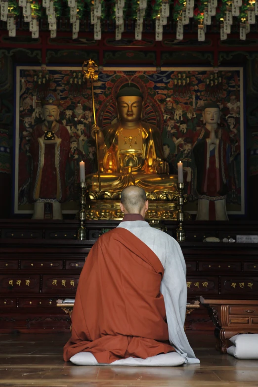 a monk in orange and white robes sitting on the ground