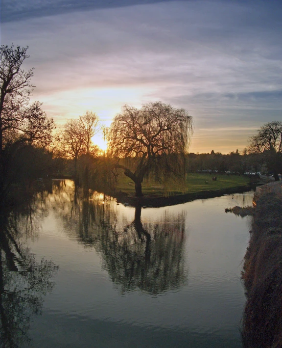 a sunset is reflecting off the still water of a river