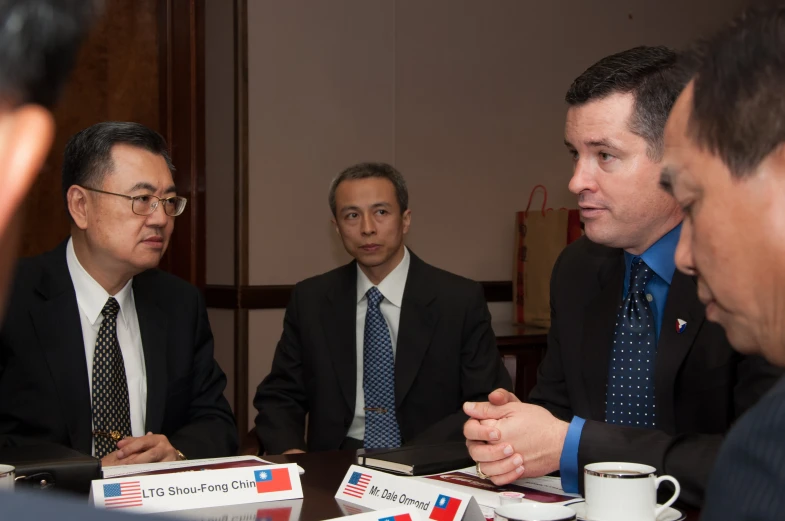 three men in business suits are sitting at a table