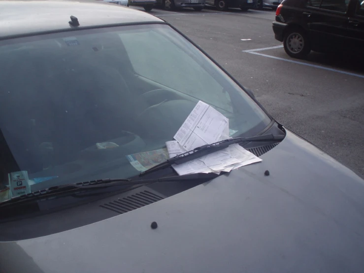 a folded paper lying on top of the windshield of a car