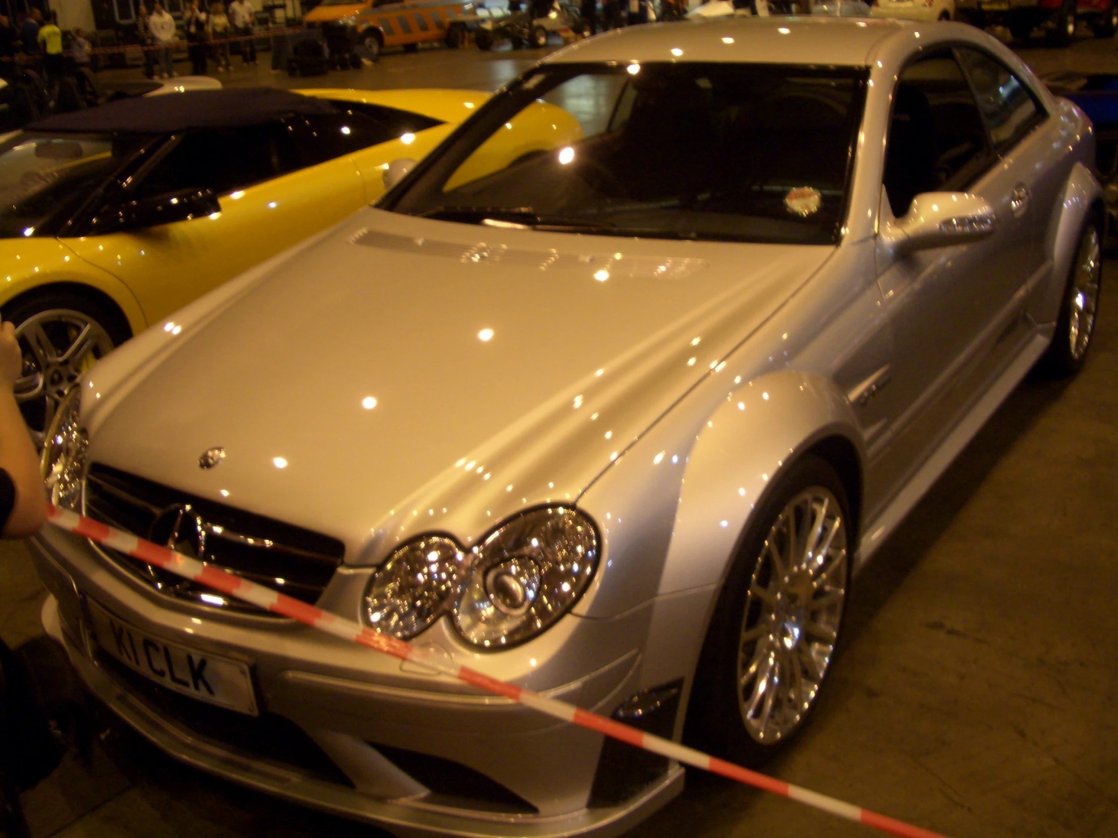 a silver car parked next to a yellow car in a parking lot