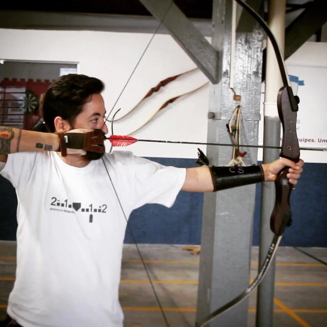 a man holds an arrow and bow in front of an archery set