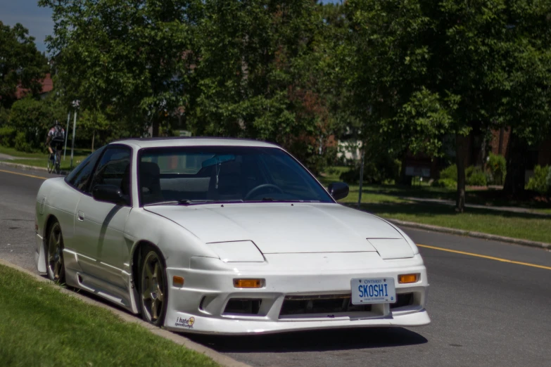 a white car driving down the road by the grass