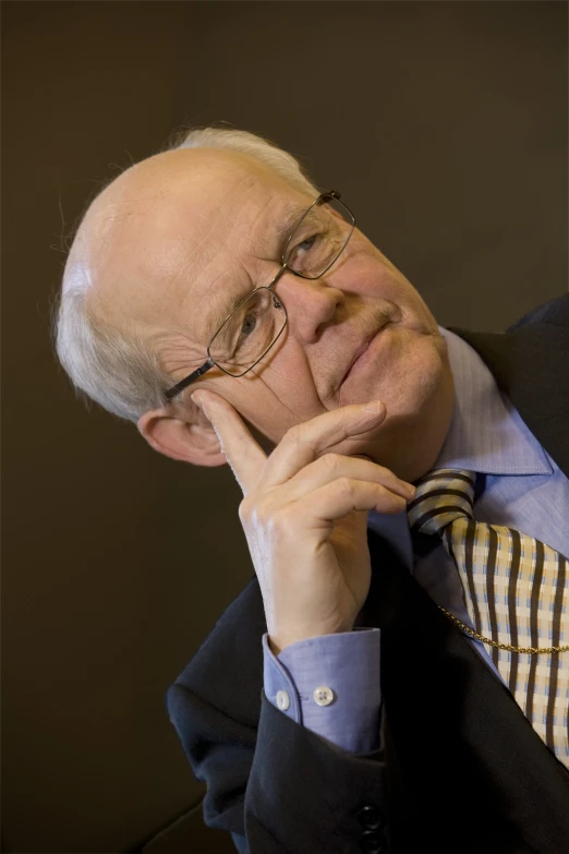 a man in glasses holding his chin up with a hand
