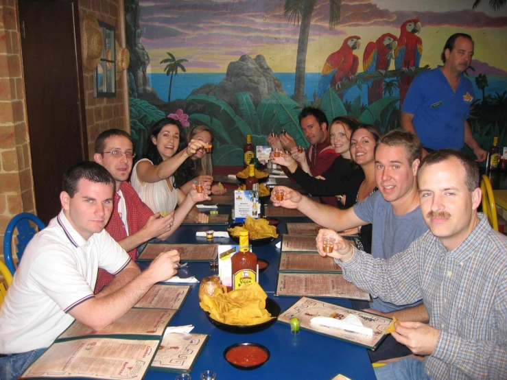 several people sitting at a table smiling with some beer