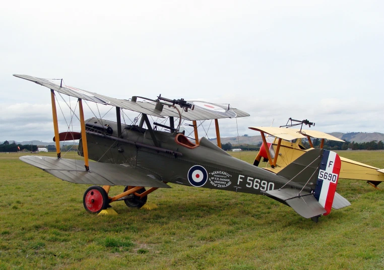 two old style airplanes parked in the grass