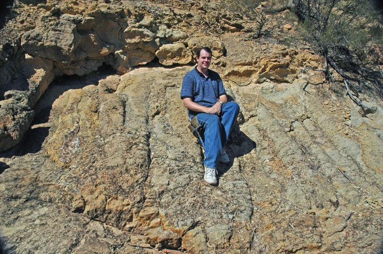 a man is sitting on top of a rock in the desert