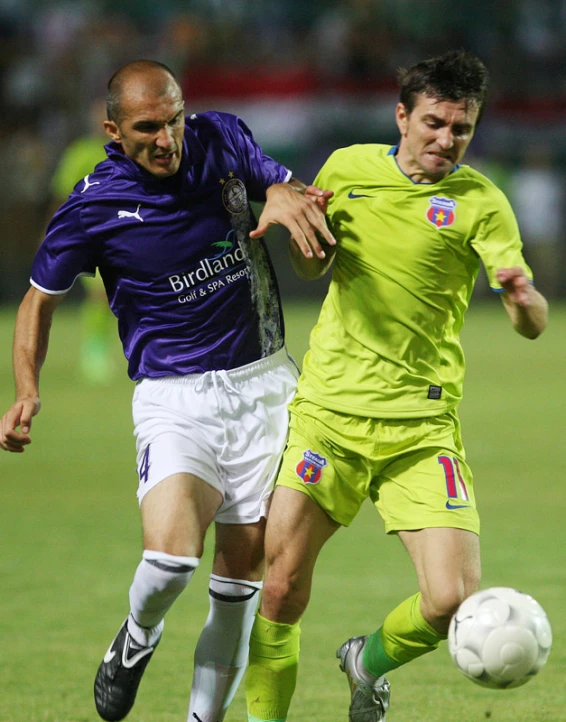 two soccer players one kicking the ball and the other chasing it