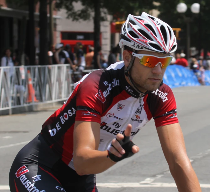 a male cyclist in a red jersey and white helmet