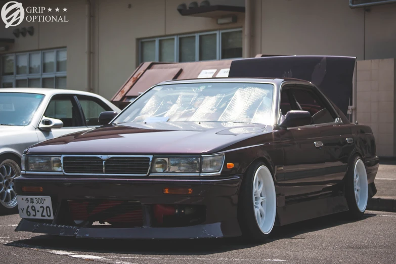 a maroon car parked next to two silver cars