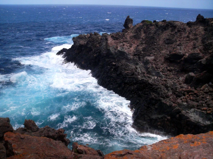 some water near some rocks and a hill