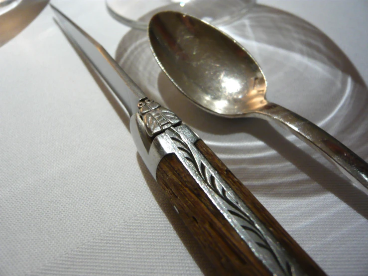 an antique set of three silver - plated teaspoons, and a spoon on a white cloth