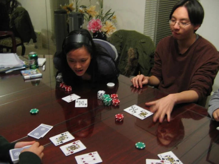 a group of people sit around a table playing cards