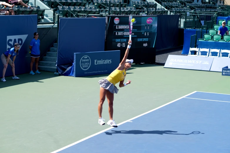 woman with arms extended holding up racket at tennis match