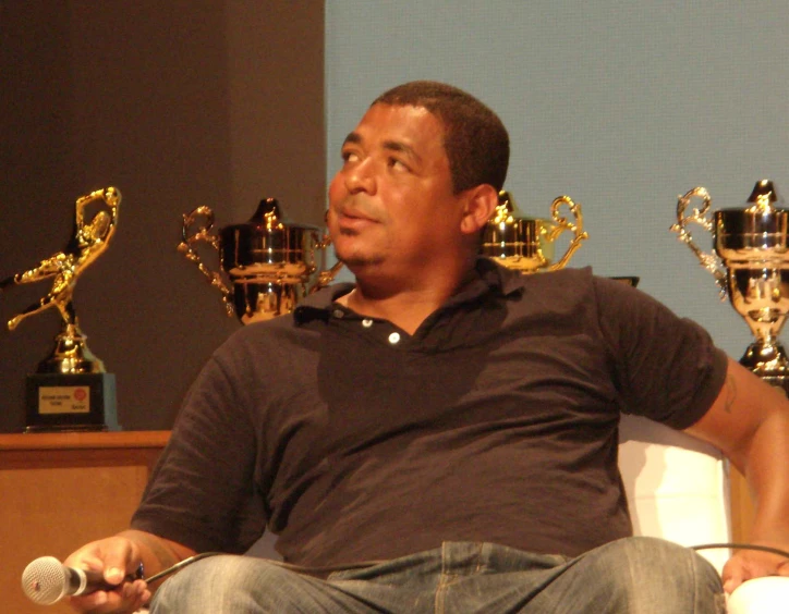 a man sitting in a chair with trophies on display