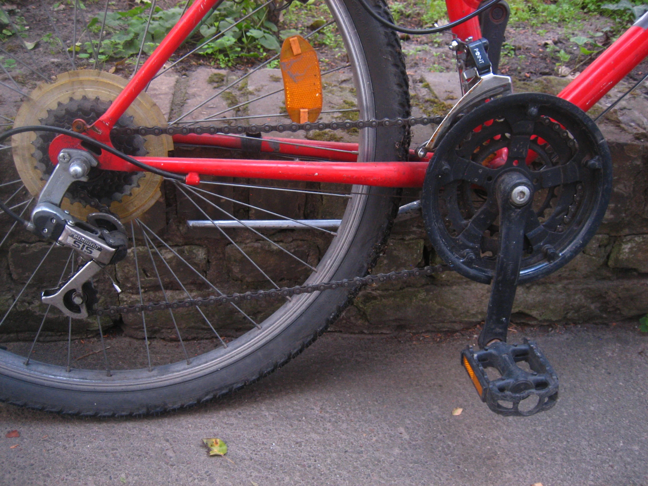 a red bicycle locked against a stone wall