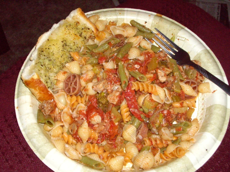 a paper plate filled with pasta and meat