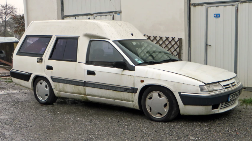 a dirty white van parked in front of a building