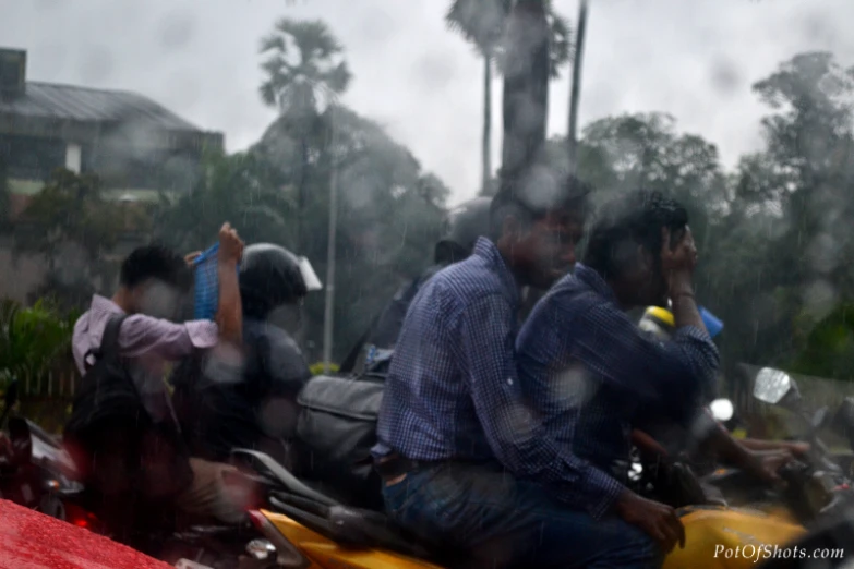 three men on a yellow motorcycle with the city in the background